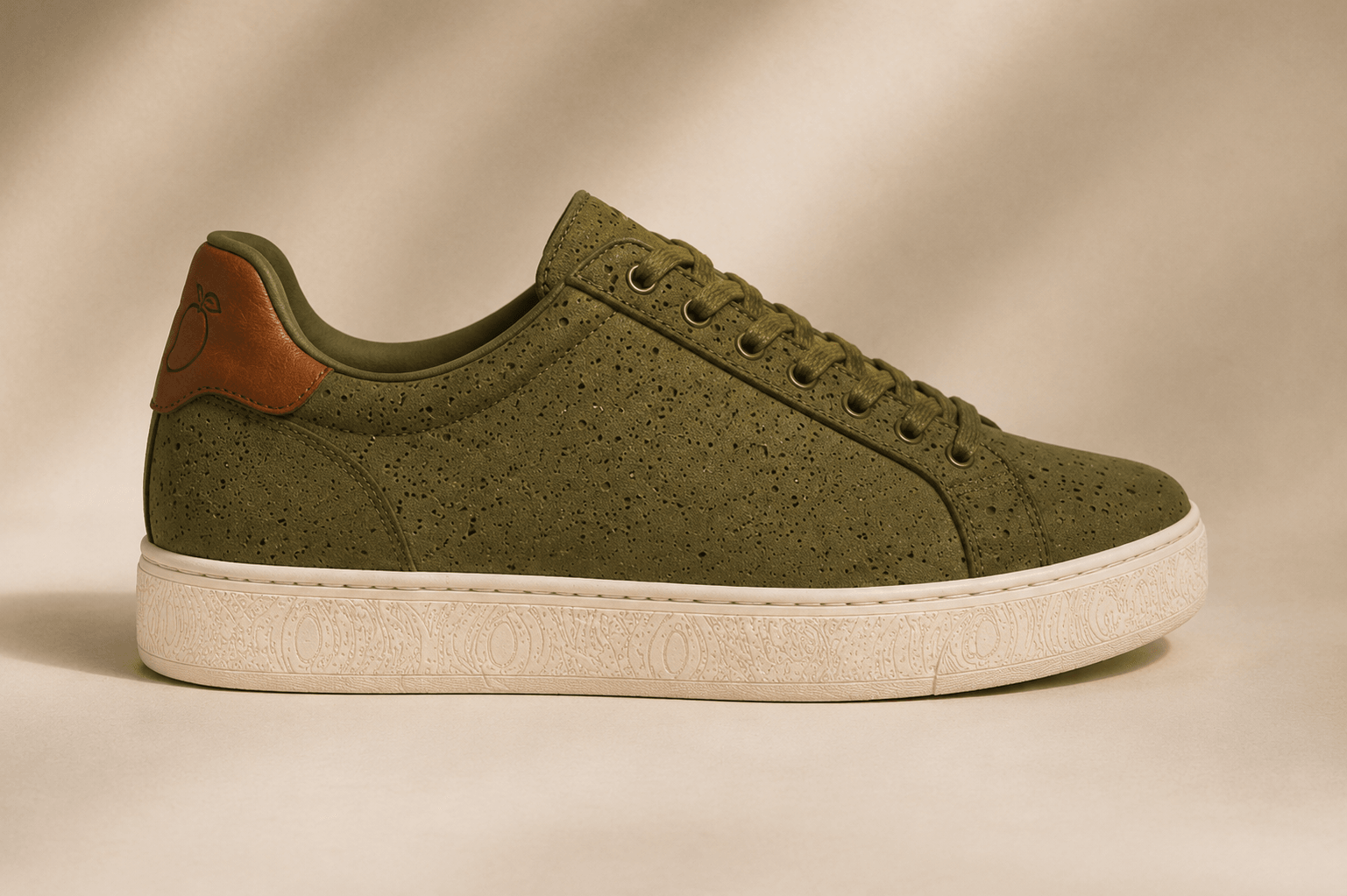 Side view of an olive perforated AAMRA court sneaker with a brown mango-embossed heel tab.