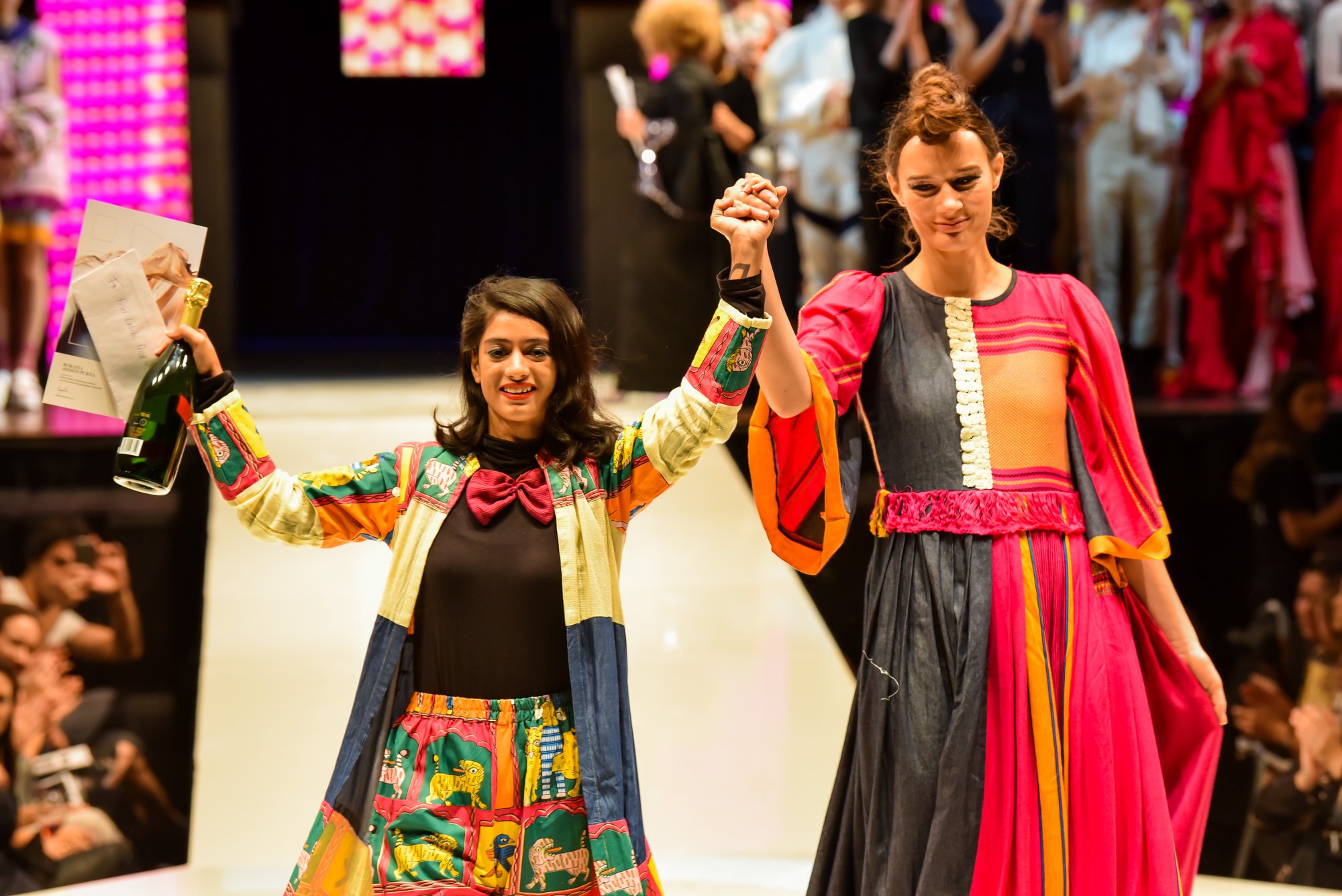Designer and model celebrating on the iD Fashion Week runway.