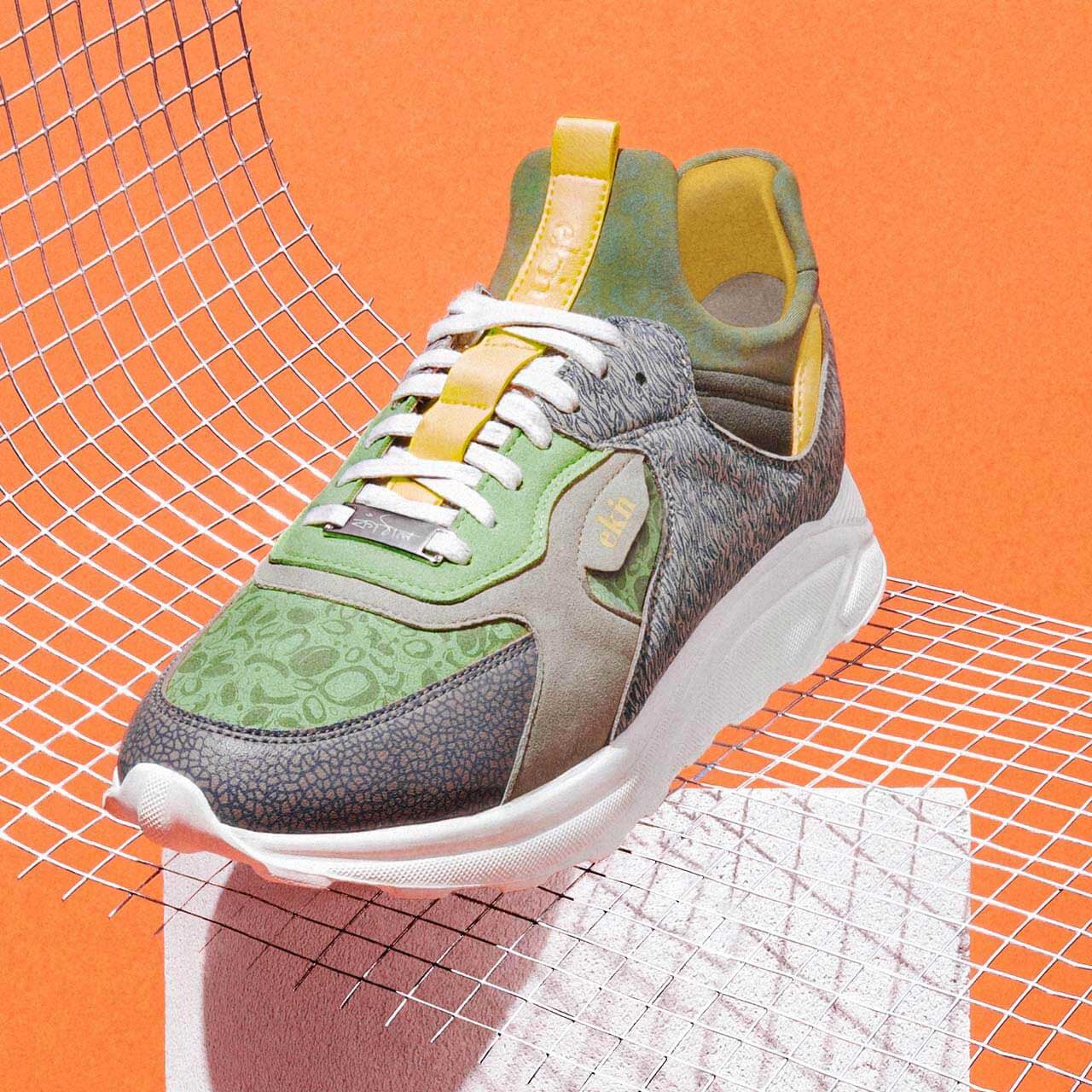 Kamthala vegan sneaker photographed on an orange ground against a wire grid.